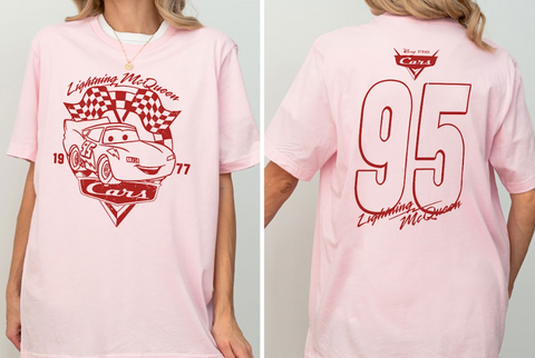 A pink t-shirt with a graphic of a car and the text "Lightning McQueen" and "77" printed on it.