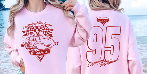 A person wearing a pink sweatshirt with a red and white design featuring a car and the text "Lightning McQueen" and "77" printed on it.