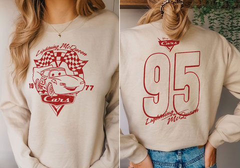 A woman wearing a white sweatshirt with a red and white design featuring a car and the text "Lightning McQueen" and "77 Cars".