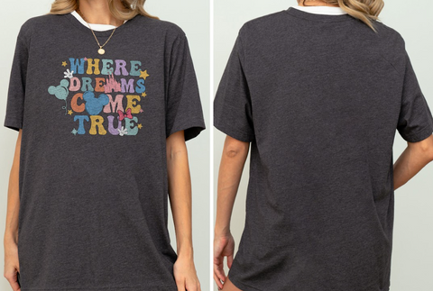 a person wearing a gray t-shirt with a colorful graphic design on it. The design features the text "WHERE DREAMS COME TRUE" along with various Disney-themed elements such as Mickey Mouse and stars.