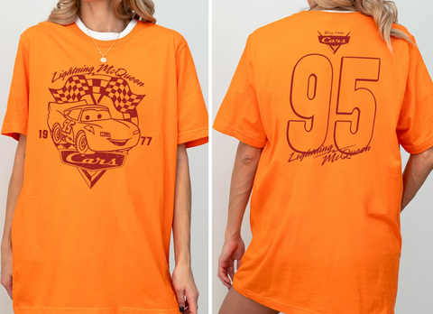 a person wearing an orange t-shirt with a graphic of Lightning McQueen from the Cars movie franchise. The t-shirt has a number "95" printed on the back.