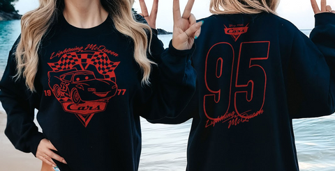 A person wearing a black sweatshirt with a red and black design featuring a car and the text "Lightning McQueen" and the number "95".