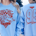 A woman wearing a light blue sweatshirt with a red and white design featuring a car and the text "Lightning McQueen" and "Cars" printed on it.