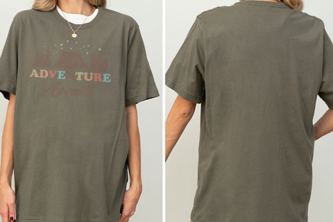 a person wearing a gray t-shirt with a graphic design featuring a mountain landscape and the text "ADVENTURE" printed on it.