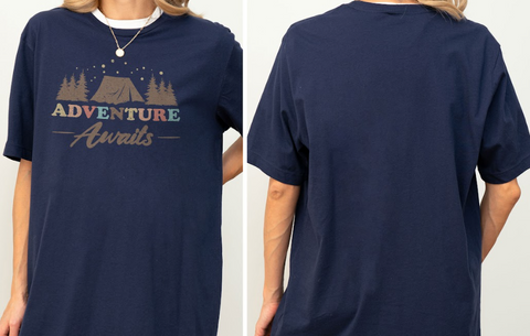 a person wearing a navy blue t-shirt with a graphic design featuring a tent and stars, along with the text "Adventure Awaits".