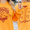 A person wearing a yellow sweatshirt with a graphic of Lightning McQueen from the Cars movie, along with the number 95.