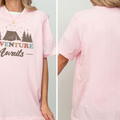 A woman wearing a pink t-shirt with the text "Adventure Awaits" printed on it.