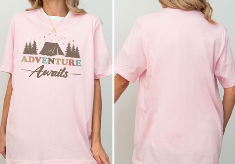 A woman wearing a pink t-shirt with the text "Adventure Awaits" printed on it.