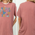 A woman wearing a pink t-shirt with a Disney-themed graphic and text.