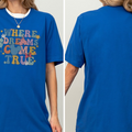 A woman wearing a blue t-shirt with the text "WHERE DREAMS COME TRUE" printed on it.