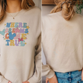 A woman wearing a white sweatshirt with a Disney-themed design and text.
