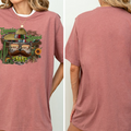 A woman wearing a pink t-shirt with a graphic design featuring a sombrero, sunglasses, and a cactus.