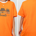 a person wearing an orange t-shirt with the text "Adventure Awaits" printed on it.