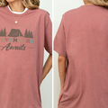 A woman wearing a pink t-shirt with the text "Adventure Awaits" printed on it.