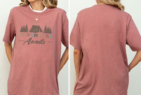 A woman wearing a pink t-shirt with the text "Adventure Awaits" printed on it.