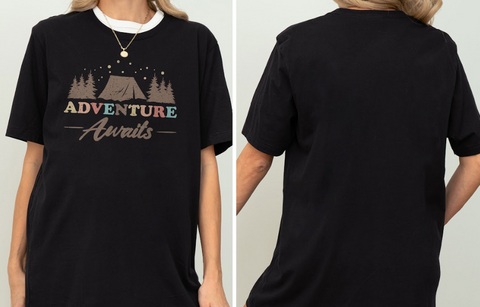 a person wearing a black t-shirt with a graphic design featuring a tent and the text "Adventure Awaits".